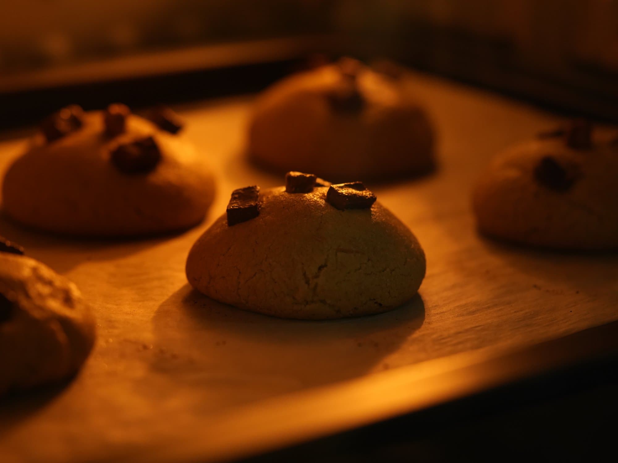A single Crumbor cookie filling the frame — cracked top, chocolate pooling, crisp edge in warm side light